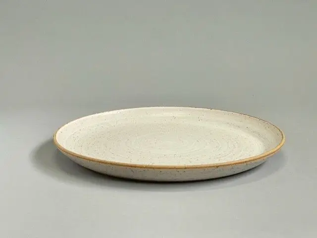 A white plate with brown rim on top of grey surface.