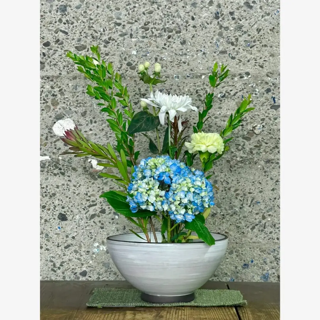 A white bowl with flowers in it on top of a table.