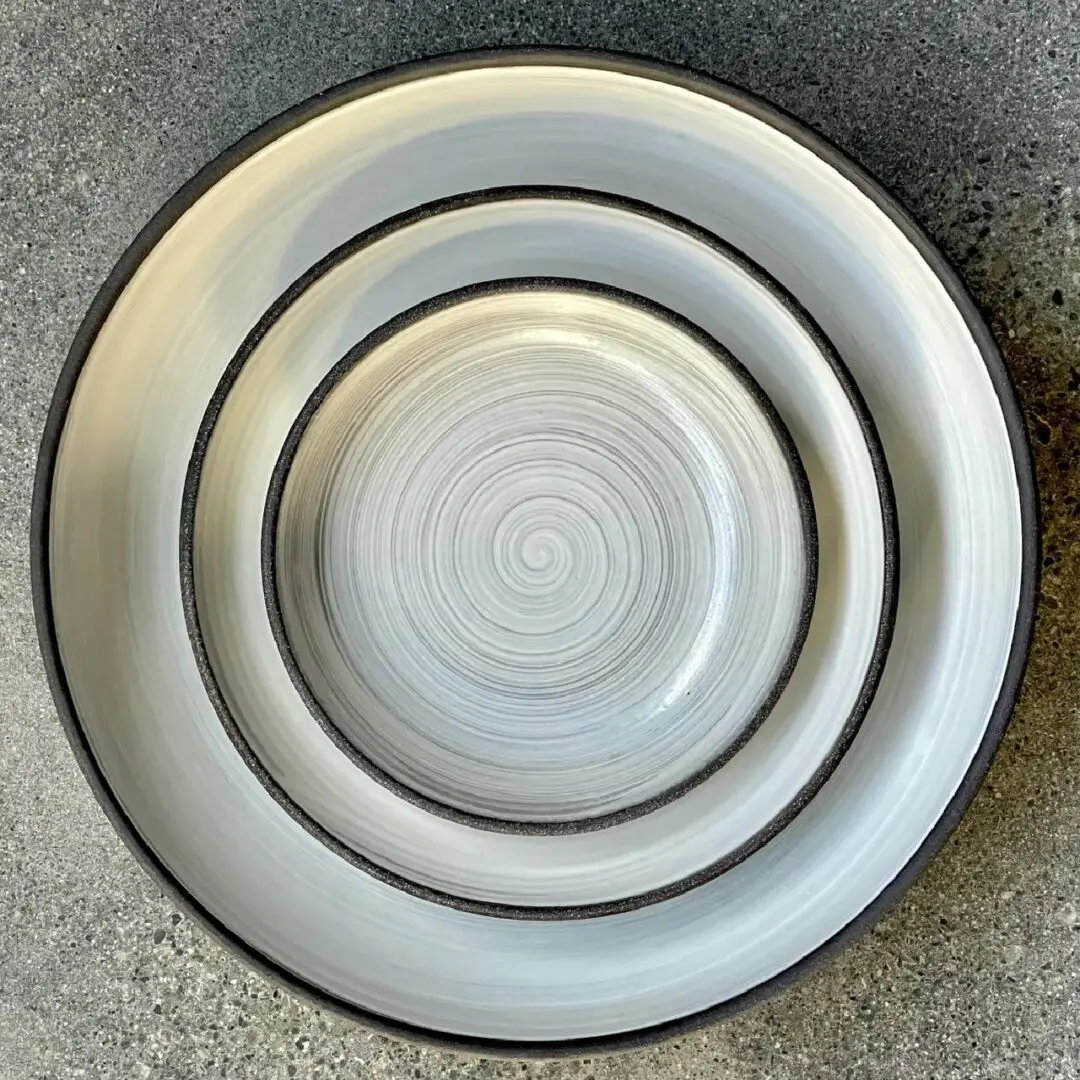 A set of three plates sitting on top of a cement floor.