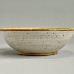 A bowl with a yellow rim and speckled white background