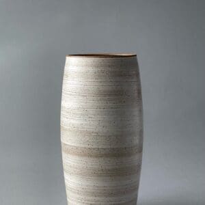 A white vase with brown stripes on the bottom