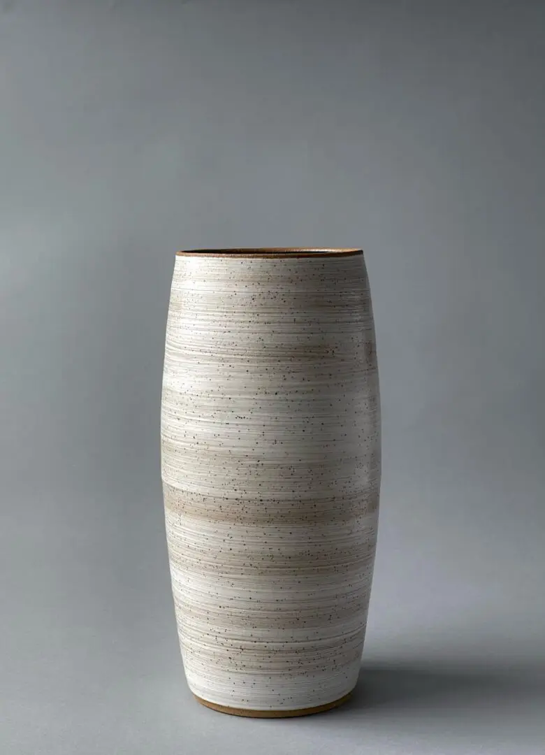 A white vase with brown stripes on the bottom