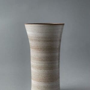 A tall white vase with brown stripes on the bottom.