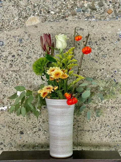 A vase filled with flowers on top of a wall.