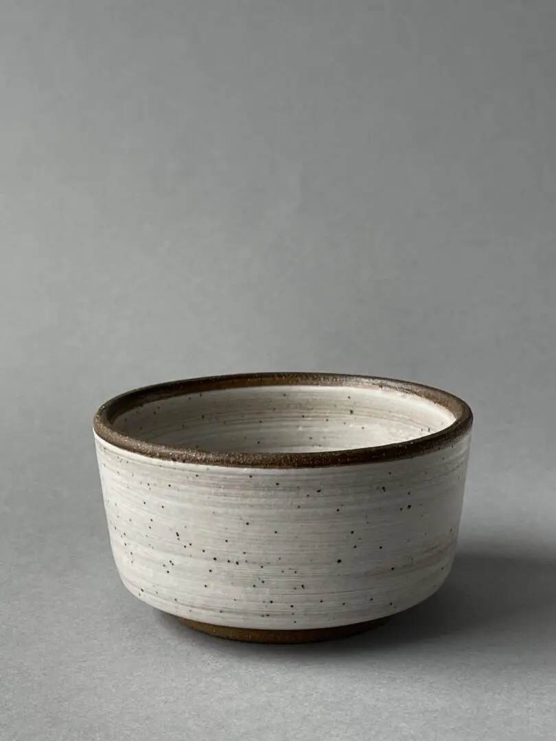 A bowl is sitting on the table and has some brown rim.